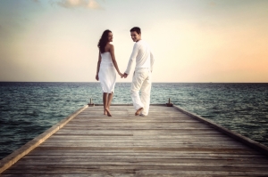 Happy loving couple in white clothes posing on a pier on Maldives